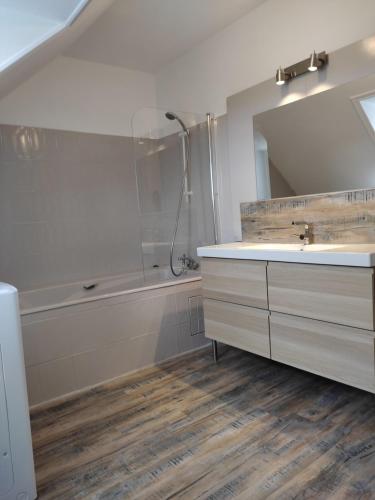 a bathroom with a sink and a tub and a mirror at résidence des dunes in Landéda