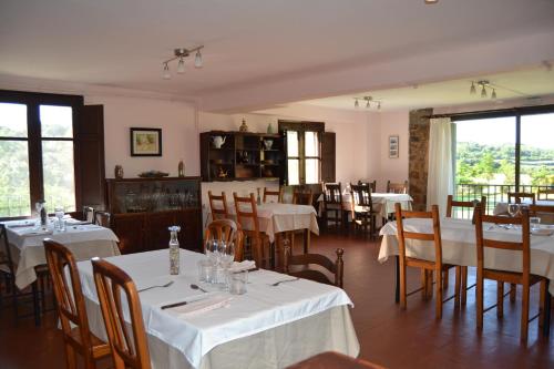 a restaurant with white tables and chairs and windows at Masia Molí de Tartareu in Tartareu