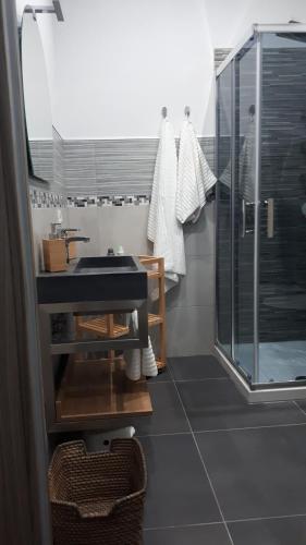 a bathroom with a glass shower and a sink at Maison Ane Marie in Avola