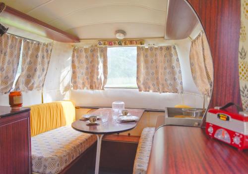 une petite chambre avec une table dans une caravane dans l'établissement Les Insolites du Domaine d'Haulmé, à Haulmé