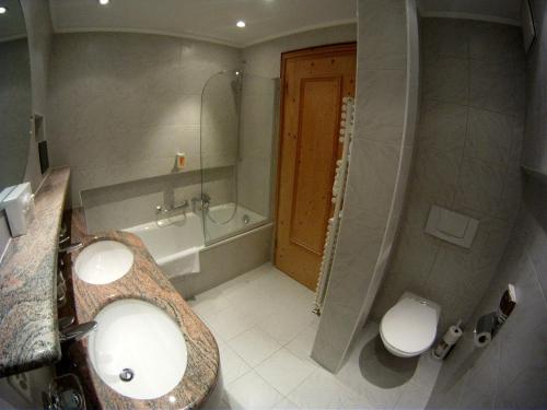 a bathroom with a sink and a tub and a toilet at Hotel Bären in St. Moritz