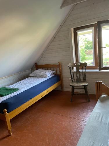 1 dormitorio con 1 cama y 1 silla en el ático en Namelis - pirtelė, en Plateliai