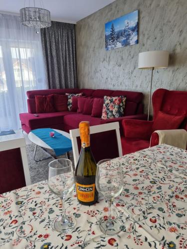 a bottle of wine sitting on a table with glasses at Apartament Czarna Góra NATALIA in Stronie Śląskie