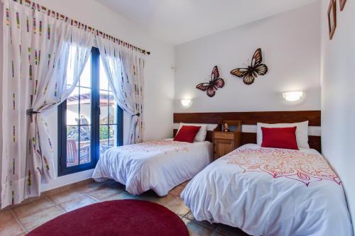 two beds in a room with butterflies on the wall at Casa Delfín Playa Blanca 2 dormitorios y piscina in Playa Blanca