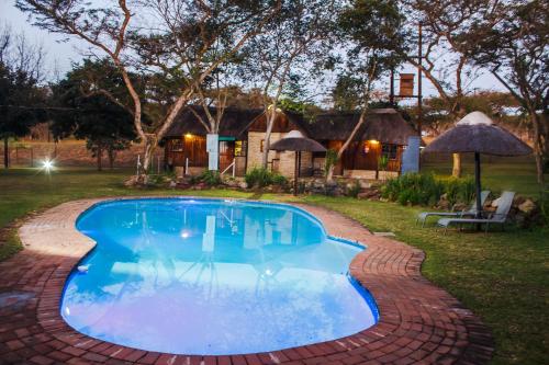 a swimming pool with a brick walkway around it at Ndalo Lodge Mbombela in Nelspruit