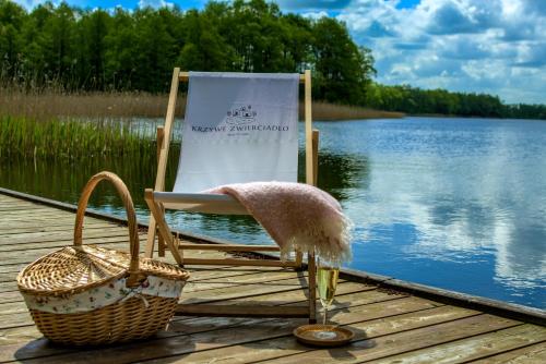 a chair sitting on a dock next to a lake at Krzywe Zwierciadło in Mrągowo