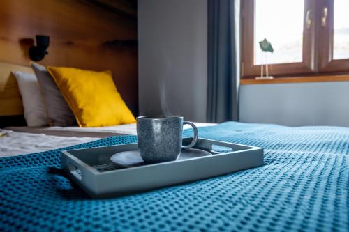 a tray with a cup on top of a bed at Krzywe Zwierciadło in Mrągowo