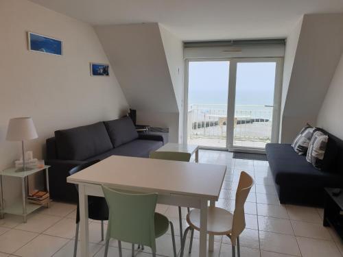 un salon avec un canapé et une table avec des chaises dans l'établissement duplex face mer wimereux, à Wimereux
