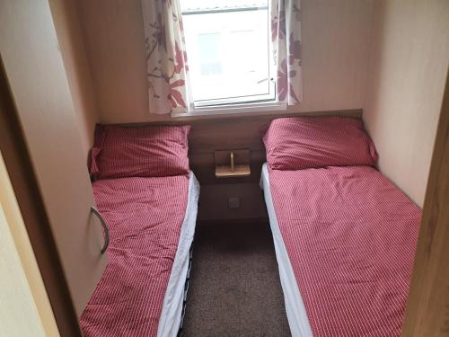 two bunk beds in a small room with a window at Haven Holiday Home Caister on Sea in Ormesby Saint Margaret