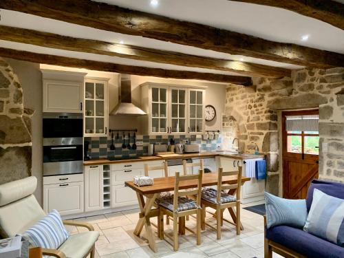 une cuisine avec des armoires blanches et une table en bois dans l'établissement Maison de Bois Royale, à Royère-de-Vassivière