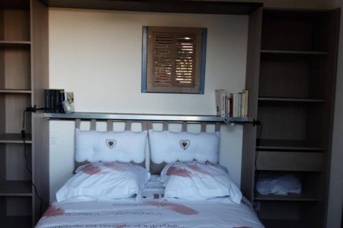 una camera da letto con testiera bianca e librerie di mon petit paradis a Saint-Blaise