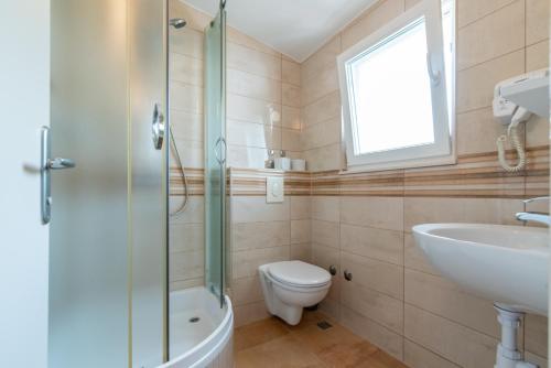 a bathroom with a shower and a toilet and a sink at Apartments Amigos in Podstrana