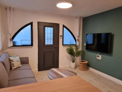 a living room with a couch and a tv and a door at LisaZ in Kefar Weradim