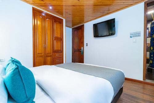 1 dormitorio con 1 cama y TV en la pared en Ayenda Casa Candilejas, en Bogotá