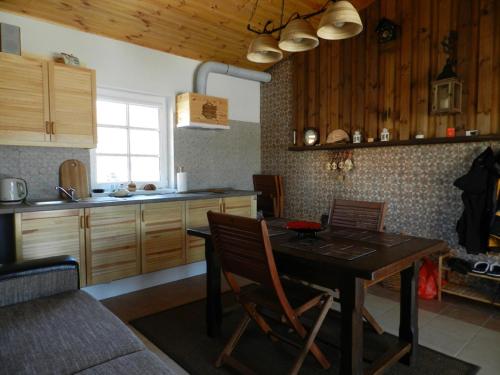 a kitchen with a dining table and a kitchen with wooden cabinets at Kontininku Namelis in Palanga