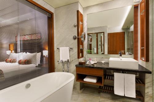 a bathroom with a tub and a sink and a mirror at Crowne Plaza Today Gurugram by IHG in Gurgaon