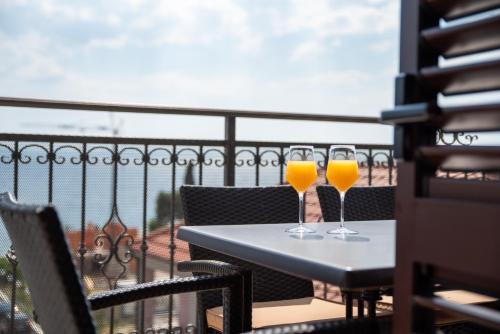two glasses of orange juice on a table on a balcony at Apartments Amigos in Podstrana