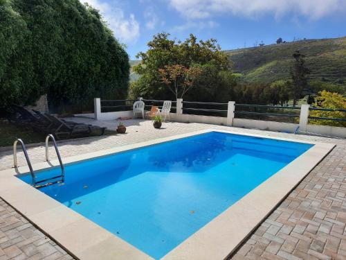 een zwembad met blauw water in een tuin bij Montejunto Villas - Casa do Plátano in Cadaval