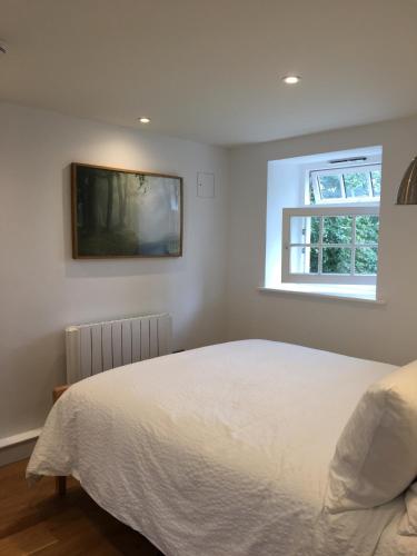 a bedroom with a white bed and a window at In the Heart of Glastonbury in Glastonbury
