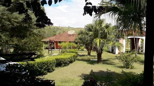 un giardino con palme e una casa di Pousada e Restaurante Village Mantovani a Lavrinhas