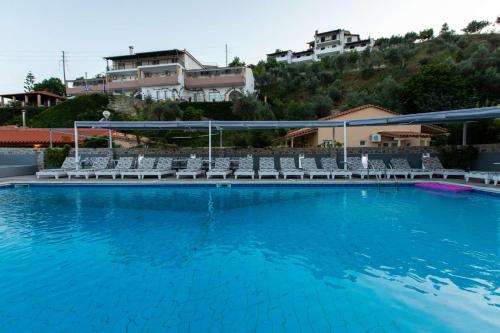 a swimming pool with blue water and white chairs at Cabana Studios & Apartments in Kolios