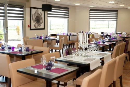une salle à manger avec tables, chaises et fenêtres dans l'établissement Armony Hotel, à Bourg-Achard