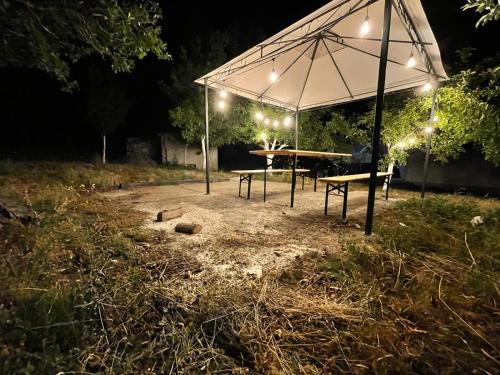 a picnic table under an umbrella at night at Riverside Guesthouse & Sauna in Vusanje