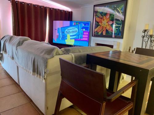 a living room with a couch and a table and a tv at Seazimbra - Luxury Apartment in Sesimbra