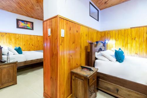 two beds in a room with wooden walls at Casa Candilejas in Bogotá