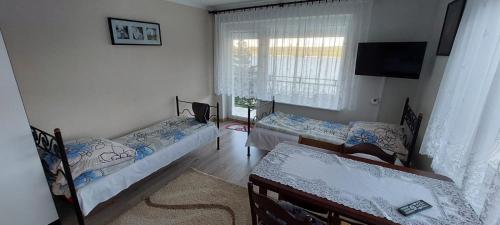 a bedroom with two beds and a tv and a window at Lemanka in Gowidlino