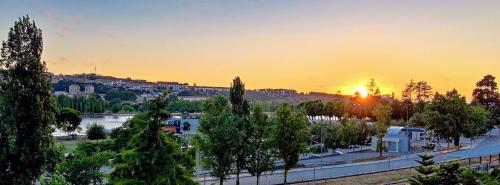a sunset over a city with a river and trees at Stylish and Elegant Studio - Best View and Location in Coimbra Downton in Coimbra