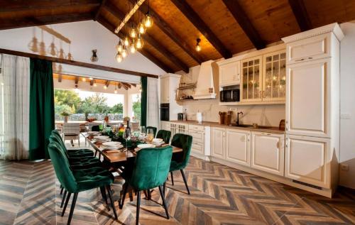 a kitchen and dining room with a table and green chairs at Luxury Villa Nature with heated private pool, sauna & fire pit in Milna