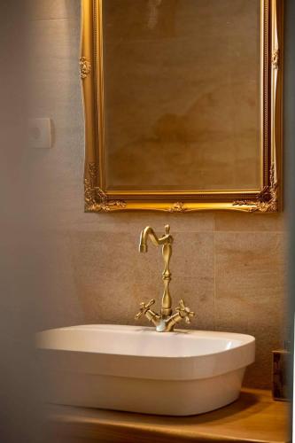 a bathroom sink with a gold faucet and a mirror at Luxury Villa Nature with heated private pool, sauna & fire pit, a short walk to the beach in Milna