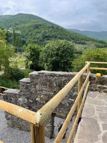 a wooden railing on top of a stone wall with a mountain at THE DORMOUSE - Il Ghiro in Reusa