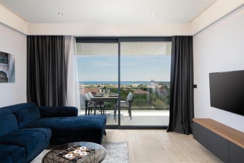 a living room with a blue couch and a large window at Boutique Apartments Kristo in Medulin