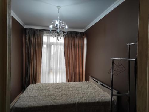 a bedroom with a bed with a chandelier and a window at 3-х ком квартира под ключ, Гагра in Gagra