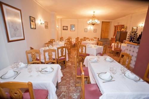 un restaurant avec des tables et des chaises blanches et un lustre dans l'établissement Hostal Miguel y Juani, à L'Alcúdia