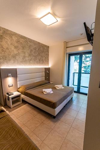 a bedroom with a bed and a large window at Hotel Monica in Riccione