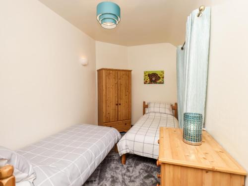 a bedroom with two beds and a wooden table at Rose Cottage in Stranraer