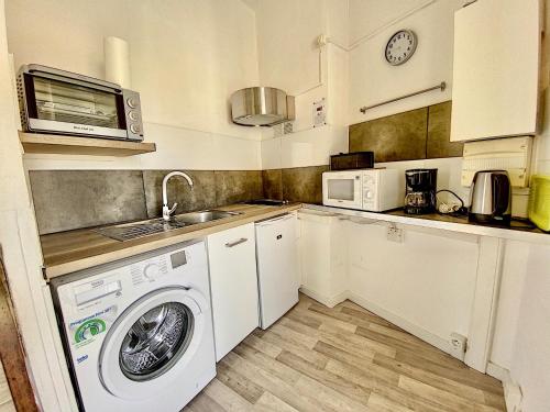 une cuisine avec un lave-linge et un micro-ondes dans l'établissement Mon Gîte Sainte Marie Climatisé, à Sète