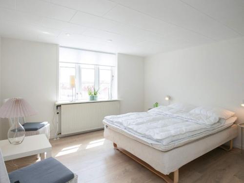 um quarto branco com uma cama grande e uma janela em 6 person holiday home in L kken em Lokken