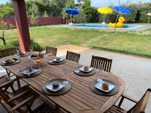 a wooden table with plates of food and wine glasses at Woof & Sun in Esmoriz
