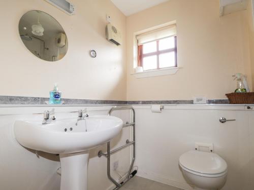 a bathroom with a sink and a toilet and a mirror at Church House in Poolewe