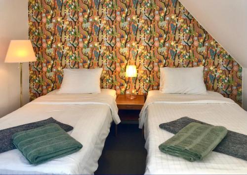 two twin beds in a room with a wallpaper at Tryde 1303 B&B på Österlen in Tomelilla
