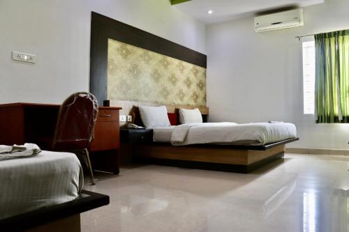 a bedroom with a bed and a chair in it at HOTEL SRI VAARI RESIDENCY in Hosūr