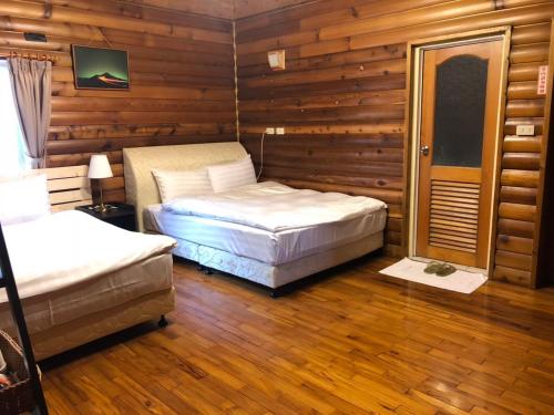 a bedroom with two beds in a room with wooden walls at Cingjing Brilliant Twins of Seattle in Renai