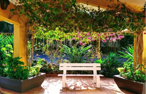 a white bench in a garden with flowers at Apartamento no Residencial Swiss Jd Europa in Santa Cruz do Sul