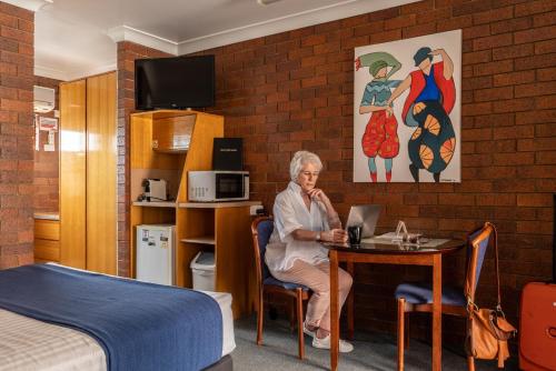 an older woman sitting at a table in a hotel room at Country Pathfinder Motor Inn in Dalby