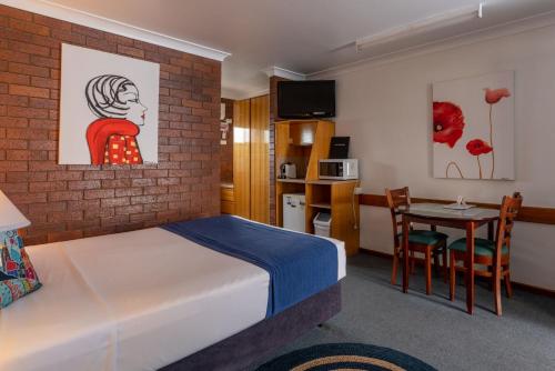 a room with a bed and a table and a kitchen at Country Pathfinder Motor Inn in Dalby