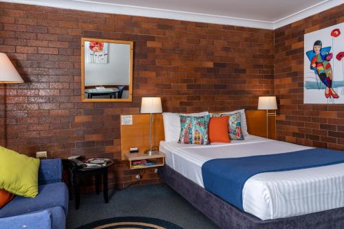 a bedroom with two beds and a brick wall at Country Pathfinder Motor Inn in Dalby